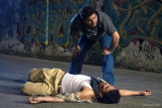 Juan (Eddie Martinez) keeps a look-out as Cesar (Karmann Bajuyo) lies on the ground hurt and wounded